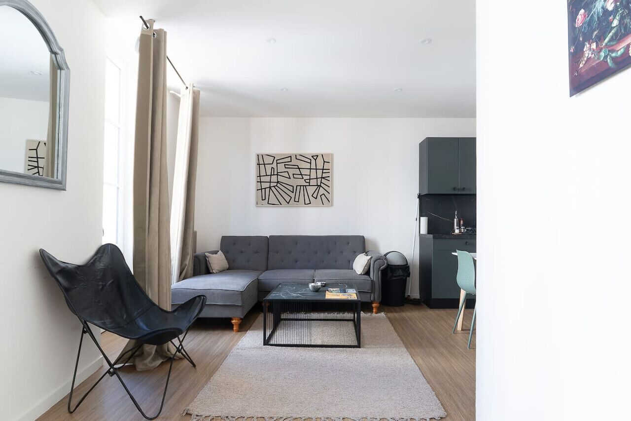 A modern living room with a grey sofa, a black chair, a coffee table, and a painting on the wall.