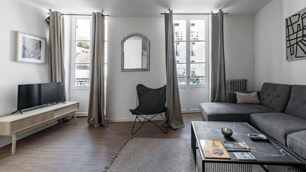 Ein modernes Wohnzimmer mit Fernseher, Sofa und Couchtisch.