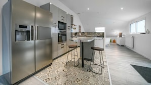 Una cocina moderna con electrodomésticos de acero inoxidable, una isla central con taburetes y una alfombra estampada.