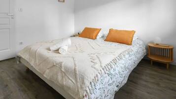 Un dormitorio con cama, dos almohadas, una mesita de noche y una puerta.