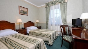 A hotel room with two beds, a desk, a chair, a television, and a window with curtains. - Ex. Best Western Hotel Zubrowka (Bialowieza)