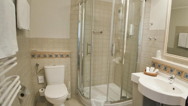 A bathroom with a toilet, a glass-enclosed shower, and a sink. - Ex. Best Western Hotel Zubrowka (Bialowieza)