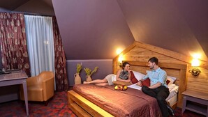 A bedroom with a wooden headboard, a desk, and a bench. - Ex. Best Western Hotel Zubrowka (Bialowieza)