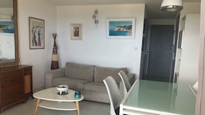 A living room with a sofa, a dining table with chairs, a coffee table, and a mirror. - Vias Plage - Apt. vue mer 4 Pers. Climatisé Avec Piscine - REF V0823 (Vias)