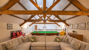 A cozy living room with a pool table, a sofa set, and a wooden ceiling structure.