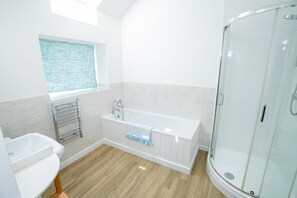 Ein modernes Badezimmer mit freistehender Badewanne, einer Glasdusche und einem Fenster mit Blick zum Himmel.