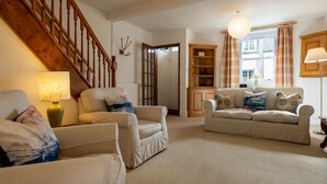 A cozy living room with a staircase, a sofa set, a wooden cabinet, and a window with curtains. - 24 Rosemary Lane - located in the heart of Beaumari (Beaumaris)