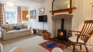 A cozy living room with a fireplace, a sofa, a chair, a television, and a large mirror. - 24 Rosemary Lane - located in the heart of Beaumari (Beaumaris)