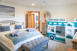 A bedroom with a bed, a bench, a dresser, a mirror, and a playhouse.