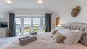 Une chambre dotée d’un grand lit, d’une télévision et offrant une vue sur l’extérieur grâce à une porte coulissante.