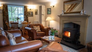 Una sala de estar acogedora con sofás de cuero, chimenea y comedor con mesa y sillas.