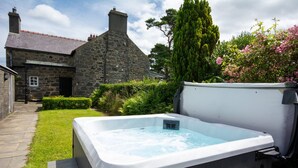 Una casa de piedra con un jacuzzi en el jardín.