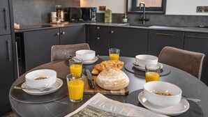 Desayuno con cruasanes, zumo de naranja y tazones de cereales sobre una mesa.