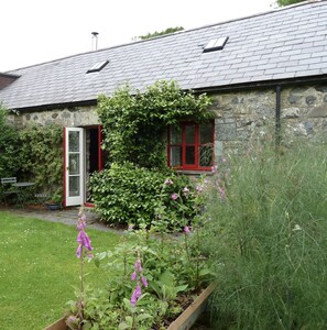 Experience a serene retreat in this charming cottage, surrounded by a peaceful garden and outdoor seating area.
