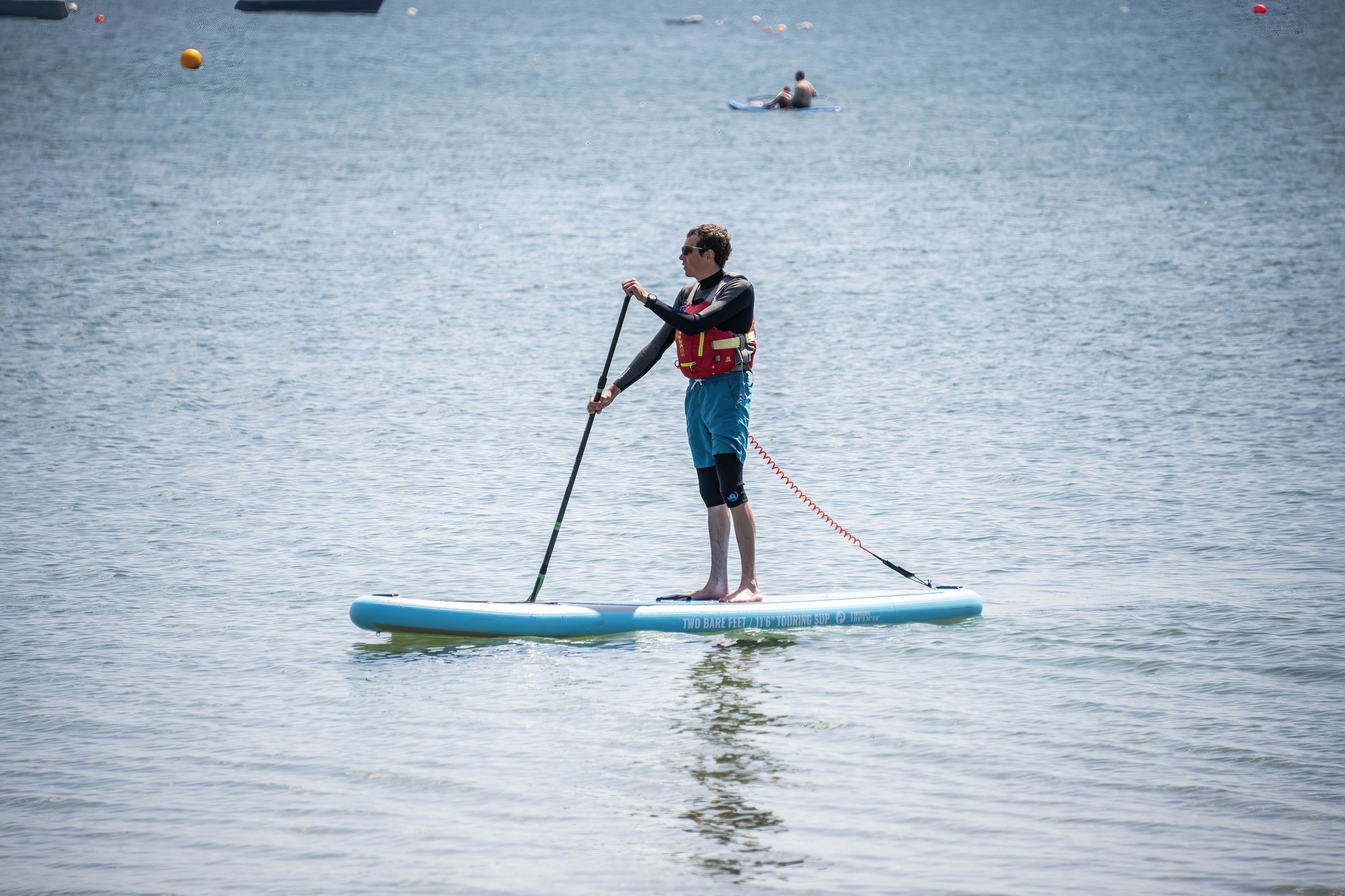 A person standing on a paddleboard in a body of water.