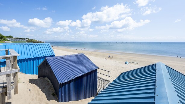 Vista sulla spiaggia con edifici a tetti blu, spiaggia sabbiosa e mare.
