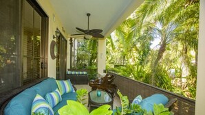 A covered porch with a sofa, a ceiling fan, and lush tropical plants. - Recently Renovated • Pacifico L604 Casa Xanadu • 2 BR Ground Floor Condo • Playas del Coco (Playas del Coco)