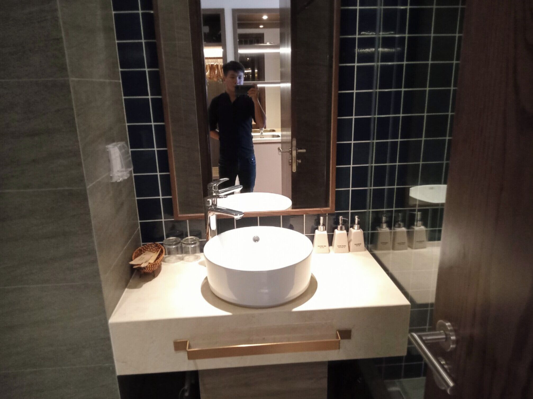 A bathroom with a round sink, a mirror, and a towel rack.
