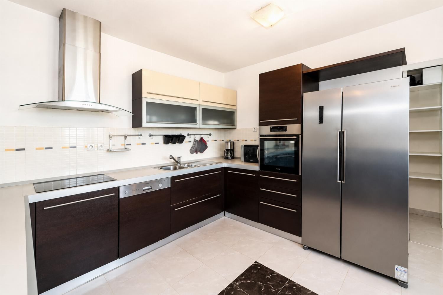 A modern kitchen with dark cabinetry, stainless steel appliances, and a tiled backsplash.
