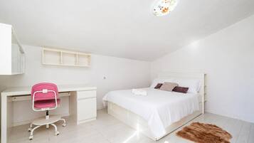 A bedroom with a bed, a desk, and a chair.