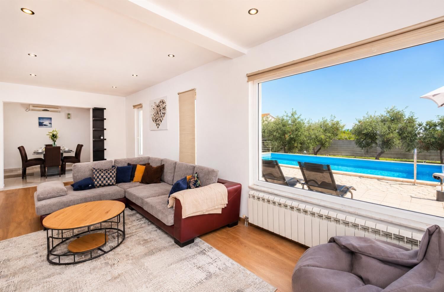 Un saló modern amb un sofà modular, una taula baixa i vista a una piscina.