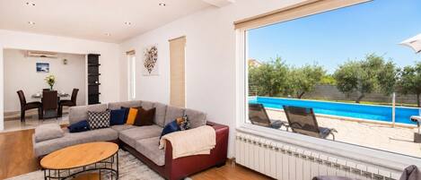 Un saló modern amb un sofà modular, una taula baixa i vista a una piscina.