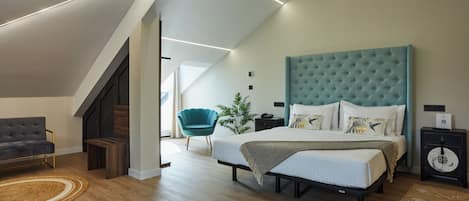 A modern bedroom with a large bed, a chair, a nightstand, and a staircase.