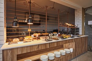 Disposição de buffet com diversos alimentos e um balcão com pratos.