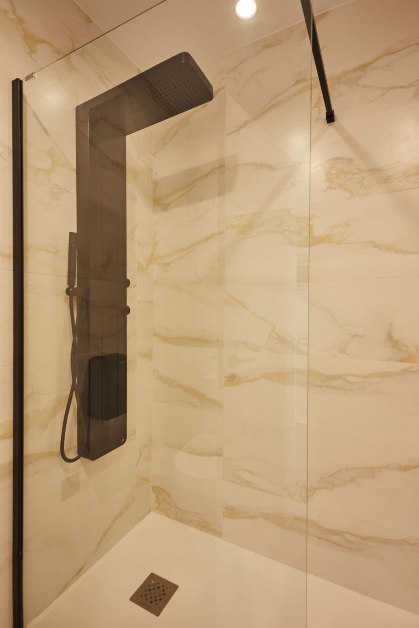 A modern bathroom with a glass-enclosed shower, marble walls, and a sleek design.