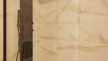 A modern bathroom with a glass-enclosed shower, marble walls, and a sleek design.