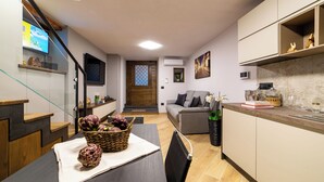 Een moderne keuken met een eethoek, een houten trap en een woonkamer met een bank en decoratieve objecten.