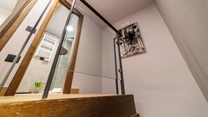 Een moderne badkamer met een houten wastafelmeubel, een douchecabine met glazen wanden en een spiegel aan de muur.