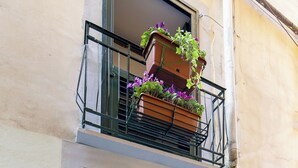 Een gebouw met een houten deur en een balkon met bloempotten.
