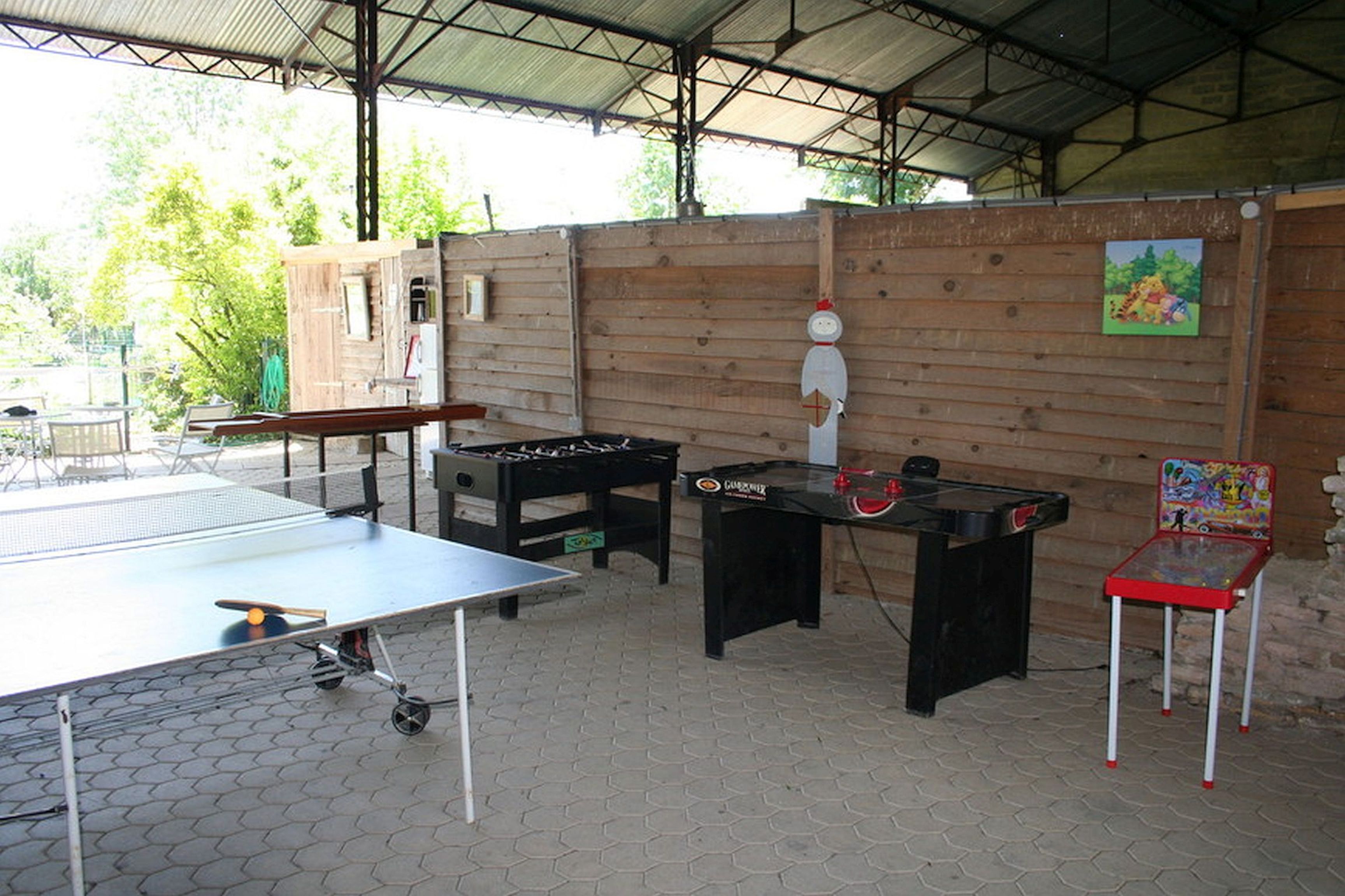 Un'area ricreativa interna con tavolo da calcio, tavolo da ping pong e un tavolo da calcio con una sedia rossa e bianca.