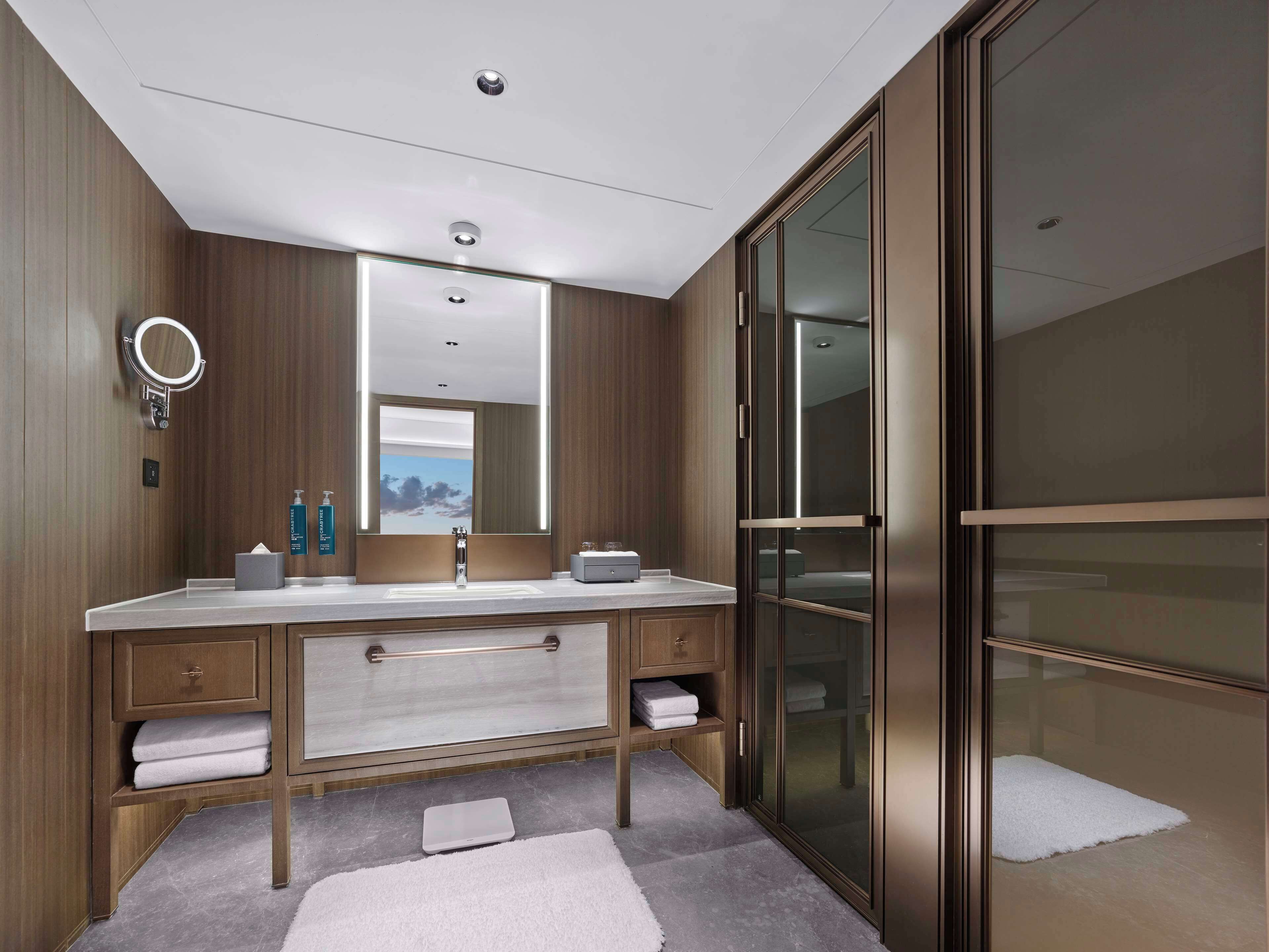A modern bathroom with a double vanity, a large mirror, and a glass-enclosed shower area.