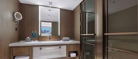 A modern bathroom with a double vanity, a large mirror, and a glass-enclosed shower area.