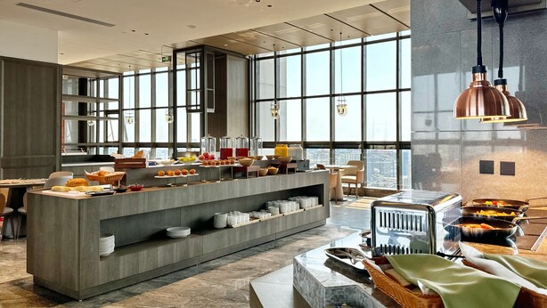 Een modern ontbijtbuffet met diverse gerechten en een uitzicht over de stad door grote ramen.