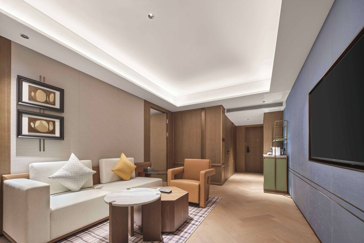 Un salon moderne avec un canapé, des fauteuils, une table basse et un téléviseur à écran plat.
