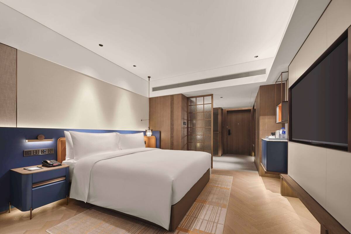Une chambre d’hôtel moderne avec un grand lit, des tables de chevet, une télévision et un dressing.