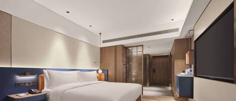 A modern hotel room with a large bed, bedside tables, a TV, and a walk-in closet.