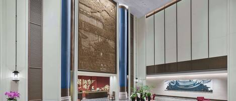 A spacious lobby with a reception desk, seating area, and a decorative wall mural.