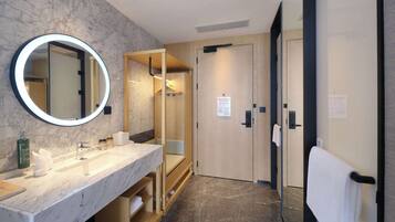 A modern bathroom with a marble vanity, a large mirror, and a shower area.