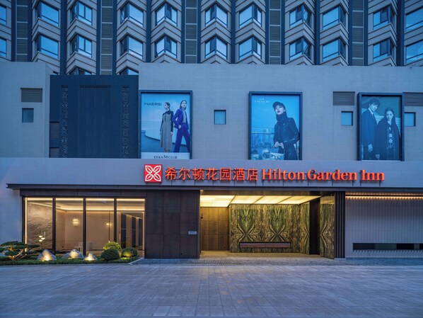 Ein Hotel Eingang mit moderner Fassade, großen Fenstern und einem gut sichtbaren Schild für Hilton Garden Inn.