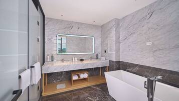 Un baño moderno con un espejo grande, una bañera y suelo de mármol.