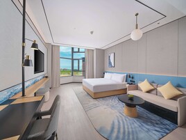 Una habitación de hotel moderna con una cama grande, un sofá, un escritorio y un televisor.