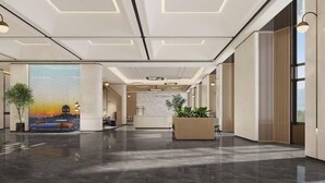 A spacious lobby with a polished floor, a seating area with a colorful mural, a reception desk, and a large plant. - Hilton Garden Inn Huludao Longxing Road (Huludao)