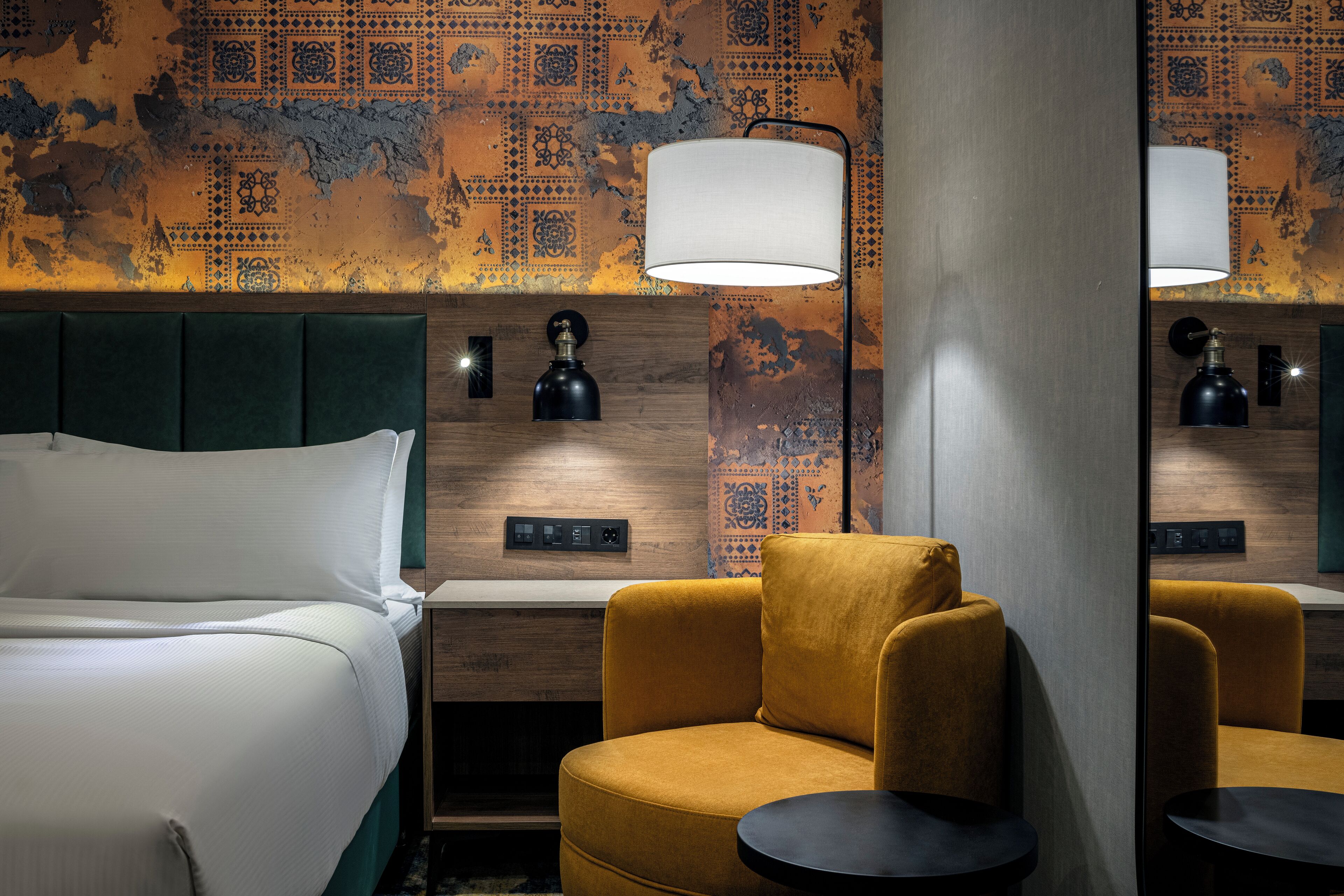 Et hotelværelse med seng, sofa, bord og lampe.