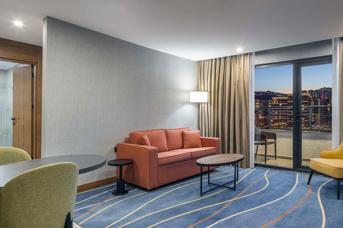 Une chambre d’hôtel équipée d’un canapé, d’un fauteuil, d’une table à manger et d’un téléviseur.
