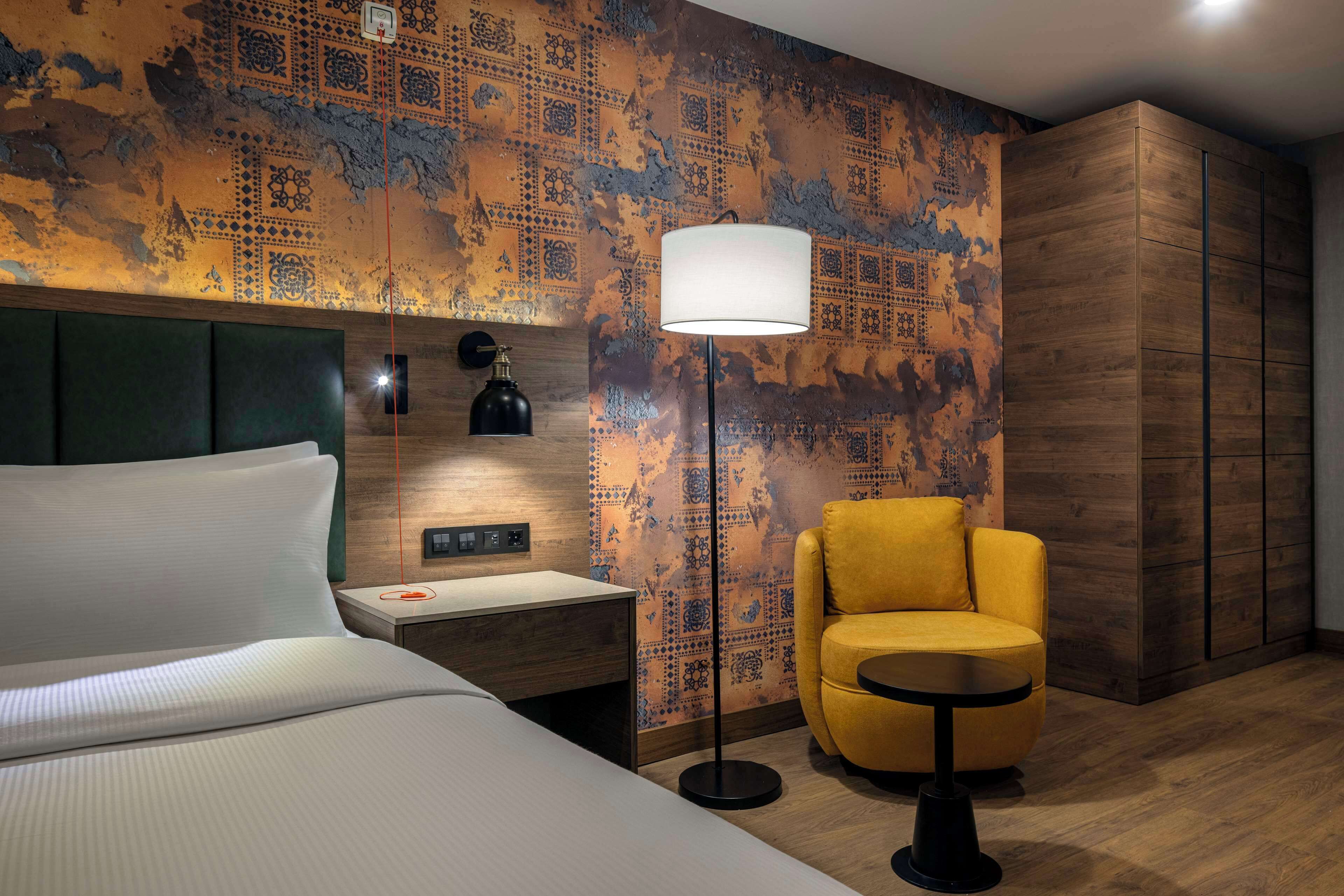 Une chambre d’hôtel comprenant un lit, une table de chevet, une lampe, une chaise et une armoire.