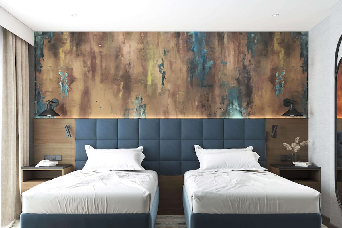 A modern hotel room with two beds, a large abstract wall mural, and a minimalist design.